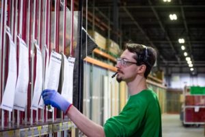 A WORKER WEARING AN AUDIO HEADSET FACES A PICKING STATION