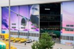 BOEING MANUFACTURING SITE RENTON WASHINGTON BLOOMBERG.jpg A PARTIALLY OPEN AIRCRAFT MANUFACTURING HANGAR SPORTS HUGE IMAGES OF PLANES ON ITS SLIDING DOORS